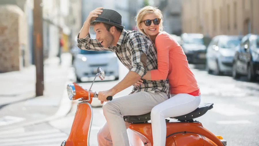Glamorous young couple riding a vintage scooter