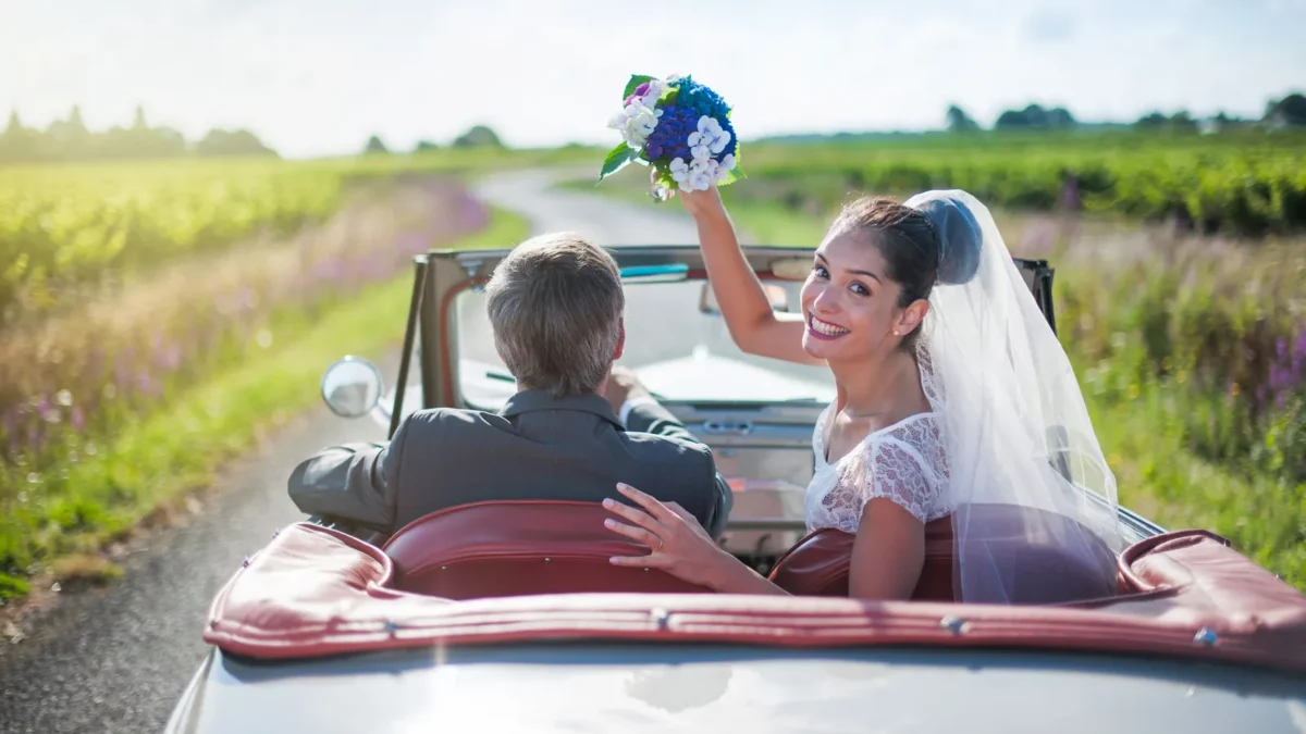 Newlywed couple is driving a retro car