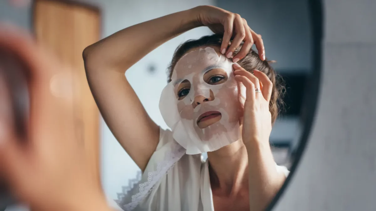 Woman applies sheet mask to her face